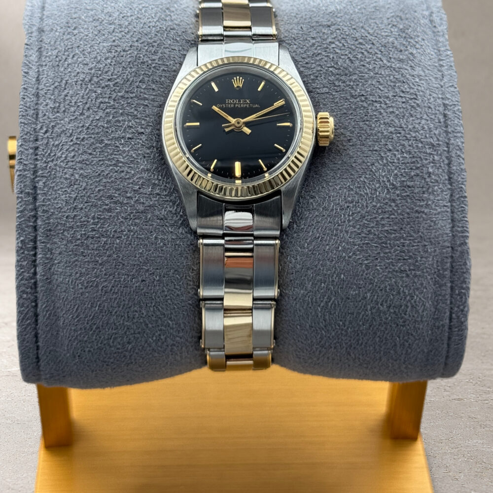 Rolex Oyster Perpetual 6619 visto frontalmente sul cuscino grigio con base dorata, con quadrante nero e bracciale bicolore.