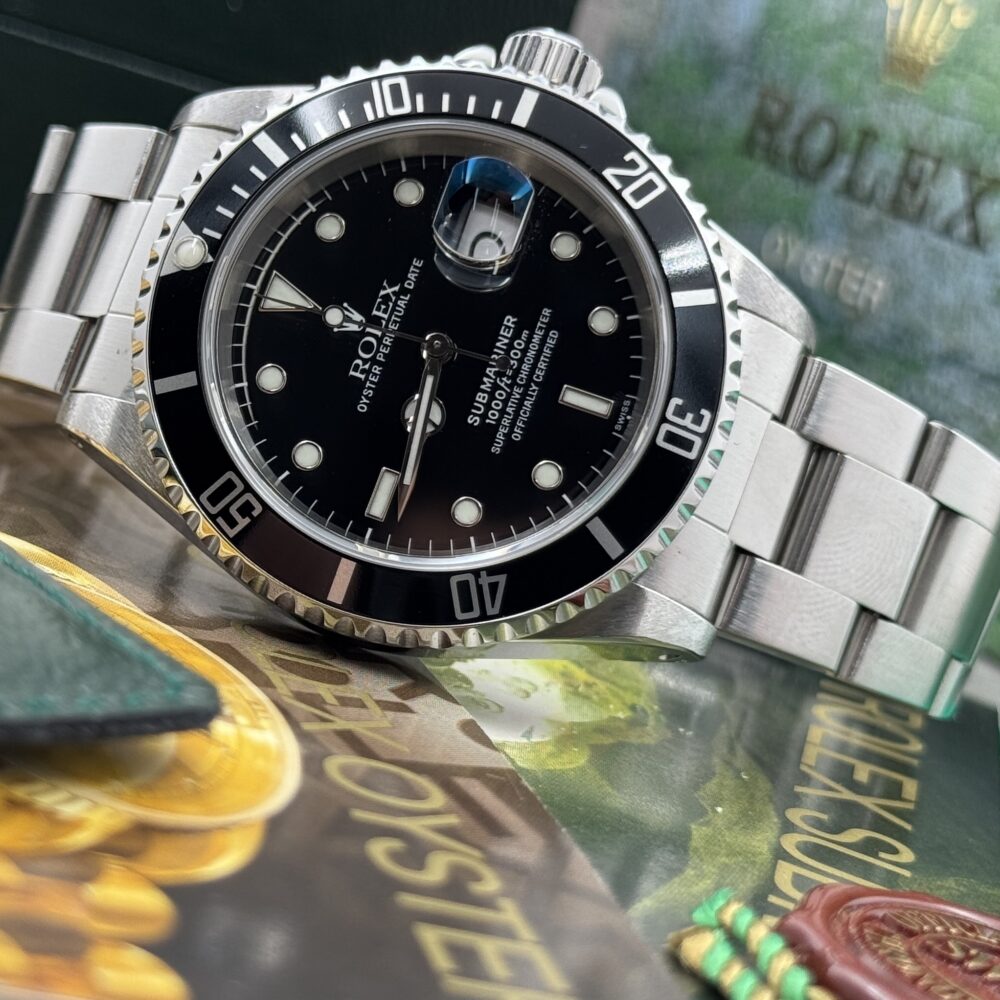 Rolex Submariner 16610 con quadrante nero, lunetta nera e bracciale in acciaio, appoggiato sui libretti Rolex.