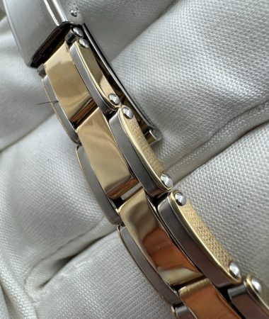Dettaglio laterale delle maglie rivettate bicolore e della chiusura del Rolex Oyster Perpetual 6619 sul guanto bianco.