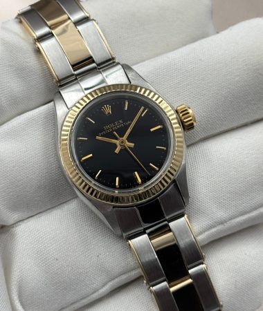 Vista frontale del Rolex Oyster Perpetual 6619 con quadrante nero e bracciale bicolore, sostenuto da un guanto bianco.